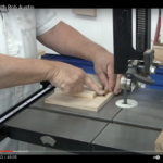 Hands guiding wooden block on bandsaw table