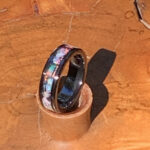 Black ring with iridescent shell inlay on wood