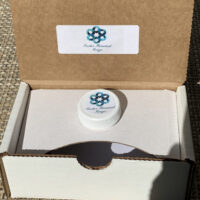 Open cardboard box with small branded jar