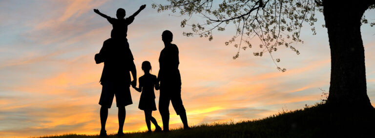 Silhouetted family at sunset under tree