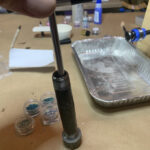 Hand using T-handle wrench on metal cylinder