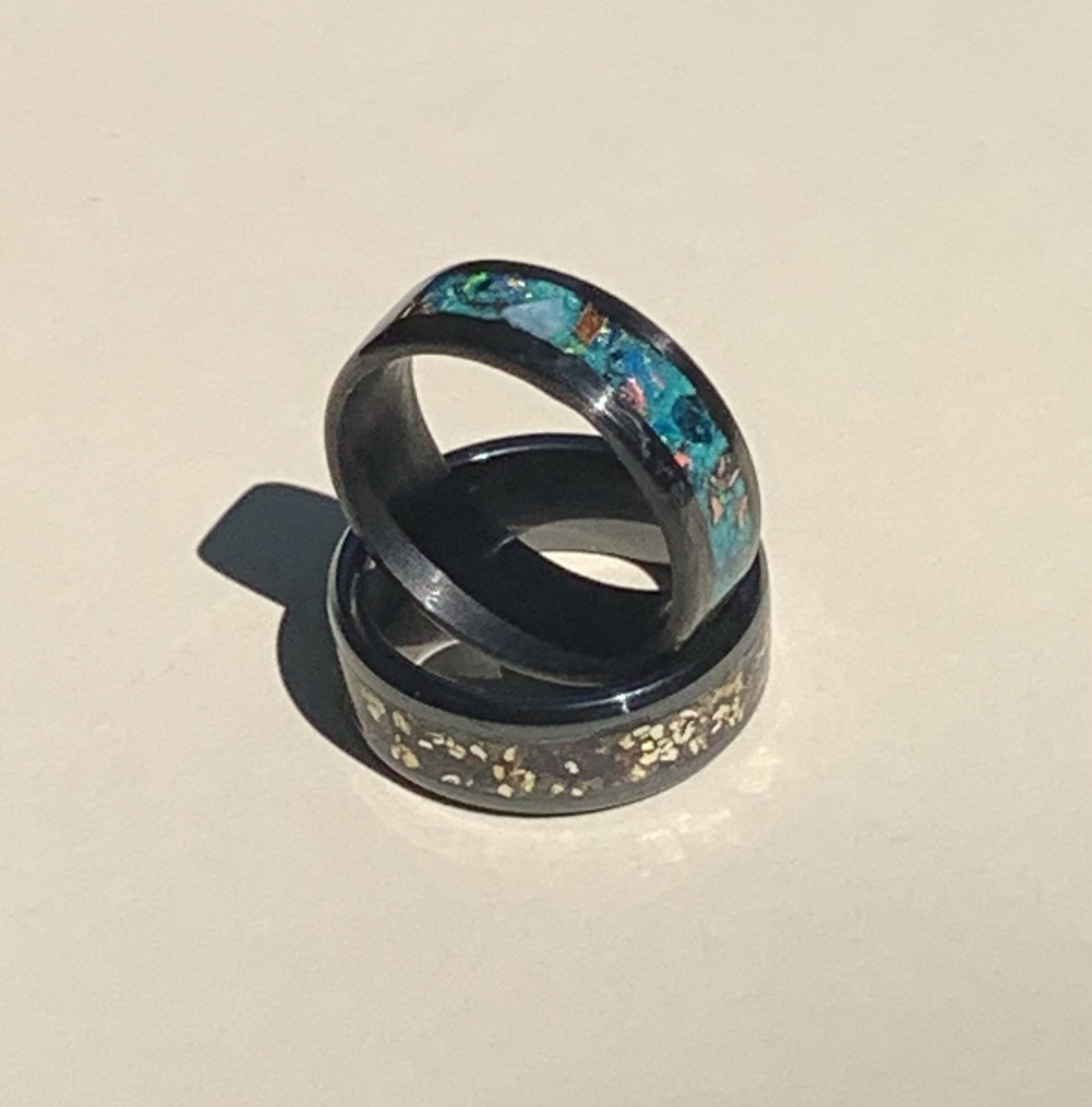 Two black rings with turquoise and gold inlay