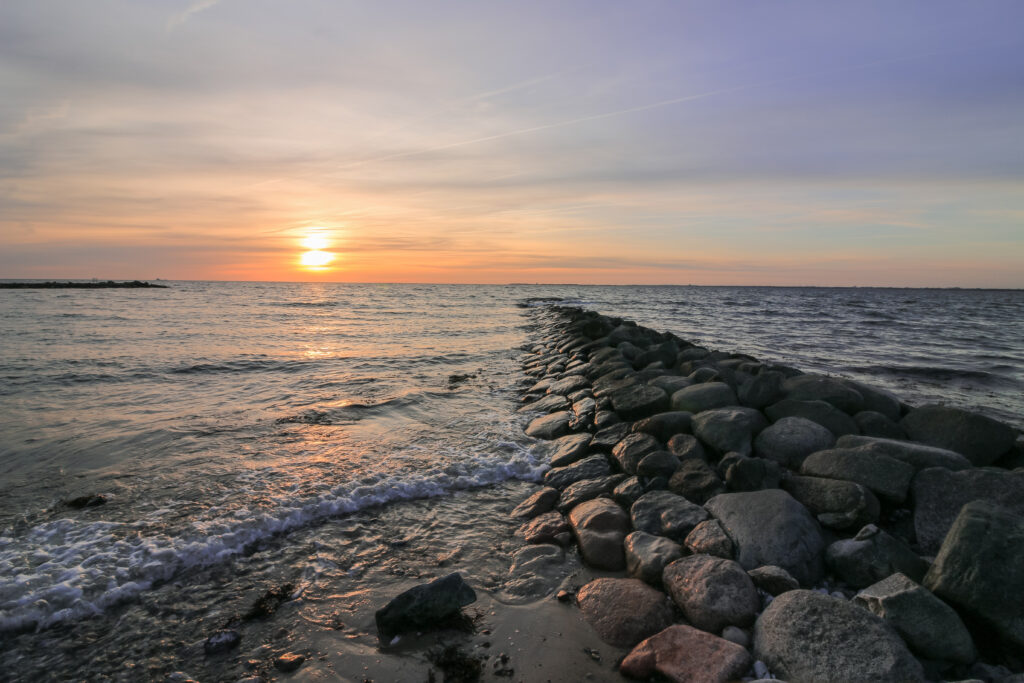 Rocky jetty extending into sea at sunset