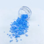 Vibrant blue crystals spilling from small glass jar