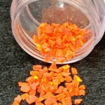 Neon orange glitter flakes spilling from jar