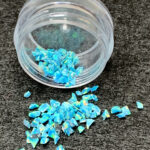 Blue glitter flakes spilled from clear container