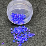 Iridescent blue glitter flakes spilling from container
