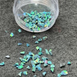 Spilled iridescent blue-green glitter flakes