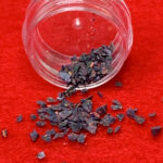 Iridescent black flakes spilled from clear jar