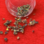 Iridescent flakes spilling from jar on red