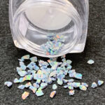 Small iridescent opal flakes spilling from jar