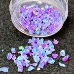 Iridescent purple glitter flakes spilled from jar