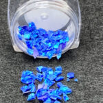 Blue iridescent glitter flakes spilling from jar