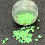 Small jar spilling neon green flakes
