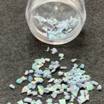 Iridescent opal flakes spilled from clear jar